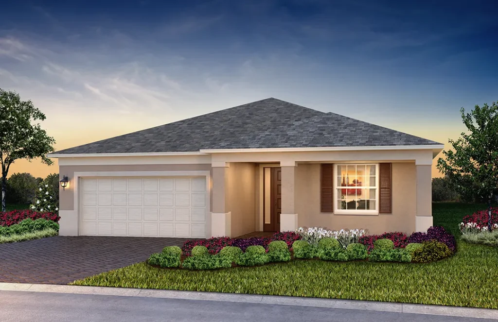 A single-story suburban home with a light beige exterior, white trim, and a gray shingled hip roof. The house features a two-car garage on the left, a central entrance, and a window with brown shutters on the right. A neatly trimmed front lawn and colorful landscaping with shrubs and flowers line the walkway and driveway.